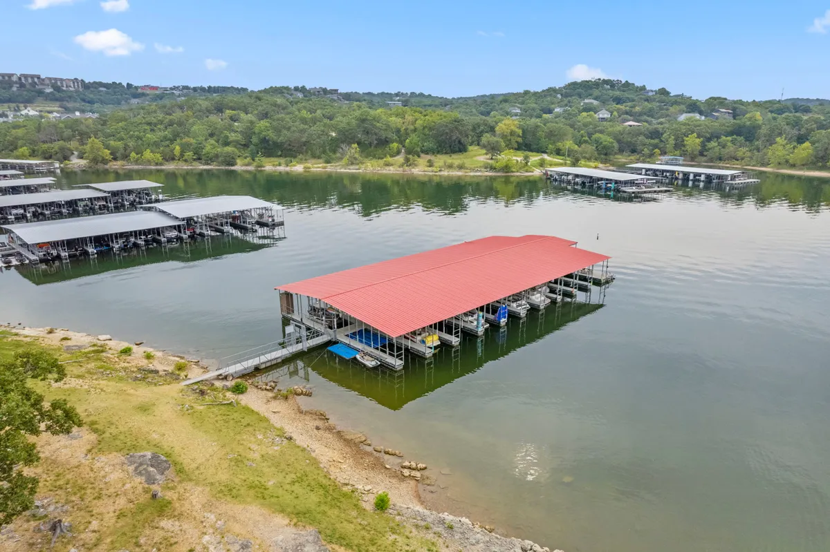 This serene image spotlights a red-roofed boat dock set amid lush greenery and calm lake waters. The tranquil atmosphere is perfect for fishing, lounging on the dock, or enjoying the sunrise. It adds a sense of quiet retreat and connection to nature.
