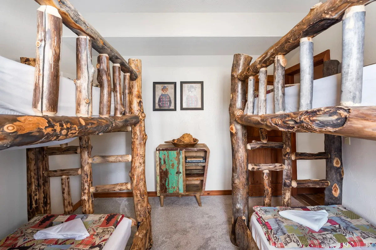 A playful bedroom with double bunk beds, decorated with charming rustic furniture and cheerful artwork. The arrangement encourages group sleepovers and fun nighttime activities for children.