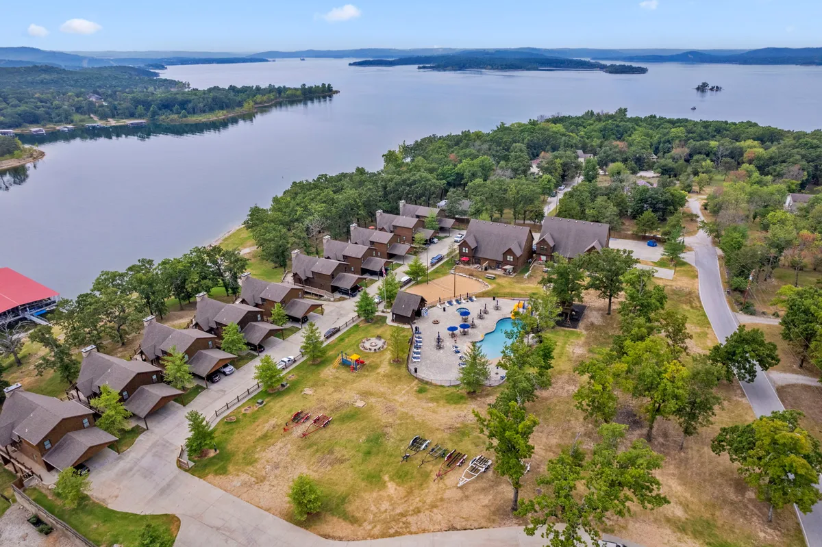 An aerial exterior shot reveals the sparkling community swimming pool, cabins, and green landscape, all nestled beside the expanse of Table Rock Lake. The pool is surrounded by lounge seating and set in a recreational, peaceful environment, inviting guests for swimming, picnicking, or simply taking in the scenery.